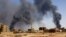 FILE - A man walks while smoke rises above buildings after aerial bombardment, during clashes between the paramilitary Rapid Support Forces and the army in Khartoum North, Sudan, May 1, 2023. 