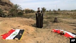FILE - An Iraqi man prays for his slain relative at the site of a mass grave believed to contain the bodies of Iraqi soldiers killed by Islamic State group militants when they overran Camp Speicher military base, in Tikrit, Iraq.