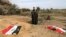 FILE - An Iraqi man prays for his slain relative at the site of a mass grave believed to contain the bodies of Iraqi soldiers killed by Islamic State group militants when they overran Camp Speicher military base, in Tikrit, Iraq.