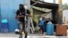 A police officer runs during a clash with gangs as a resident of the Delmas 30 neighborhood flees his home due to gang violence, in Port-au-Prince, Haiti, Feb. 26, 2025. 