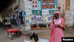 A woman speaks on her mobile phone as she stands in front of campaign posters of the Samm Sa Kaddu (Keep Its Word) coalition for the upcoming early legislative election in Dakar, Senegal, Nov. 11, 2024.