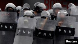 Police officers shield themselves during clashes with opposition supporters after the Organization of American States rejected a declaration of victory for Honduran President Juan Orlando Hernandez in a sharply disputed election, in Tegucigalpa, Honduras,