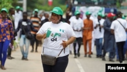 A woman waves a flag while participating in an Independence Day celebration in Abuja, Nigeria, Oct. 1, 2024. 