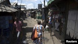 FILE - A woman walks on a street at the Mukuru Kwa Njenga slum in the capital Nairobi, Kenya, March 16, 2015. 