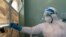FILE - A medical staff member wears protective equipment while closing a window at the Wilkins Infectious Diseases Hospital in Harare, March 11, 2020.