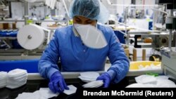 Seorang pekerja menumpuk masker N95 saat proses produksi di Protective Health Gear (PHG) di Paterson, New Jersey, AS, 14 Januari 2022. (Foto: REUTERS/Brendan McDermid)