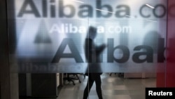 Employee seen behind glass door of Alibaba's company headquarters on the outskirts of Hangzhou, China, April 23, 2014.