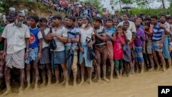 FILE - Rohingya Muslim men, who crossed over from Myanmar into Bangladesh, wait for their turn to collect food items distributed by aid agencies in Balukhali refugee camp, Bangladesh, Sept. 19, 2017. 