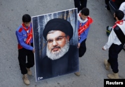 Pria membawa potret pemimpin Hizbullah Lebanon, Sayyed Hassan Nasrallah, di Kota Jbaa, Lebanon selatan, 23 November 2023. REUTERS/Alaa Al-Marjani