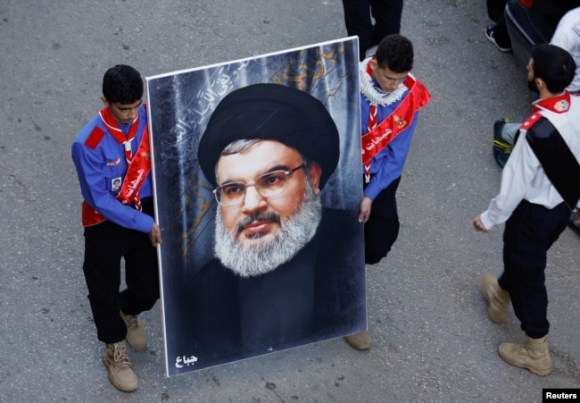 Pria membawa potret pemimpin Hizbullah Lebanon, Sayyed Hassan Nasrallah, di Kota Jbaa, Lebanon selatan, 23 November 2023. REUTERS/Alaa Al-Marjani