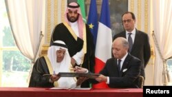 French Foreign Minister Laurent Fabius (R), exchanges documents with Dr. Hashim Yamani, the President of King Abdullah City for Atomic and Renewable Energy, after signing an agreement between France and Saudi Arabia, at the Elysee Palace in Paris, June 24, 2015. 