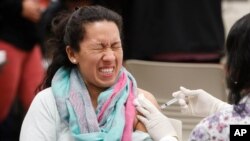 FILE - A women reacts to getting an influenza vaccine shot at Eastfield College in Mesquite, Texas, Jan. 23, 2020.