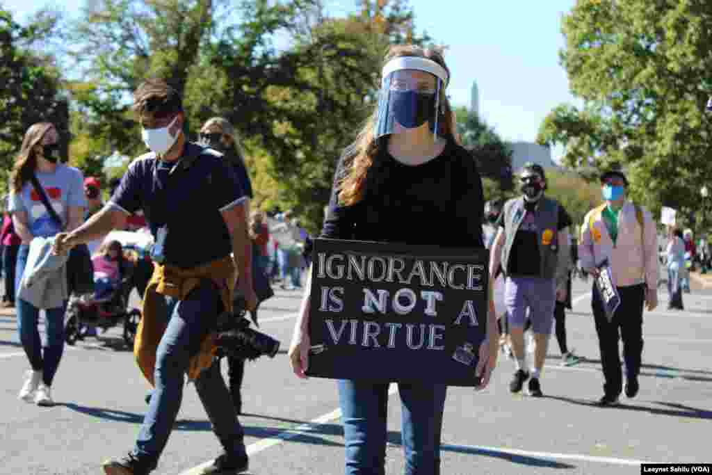 Uma mulher exibe um cartaz dizendo "Ignorância não é virtude", Marcha das Mulheres, 17 outubro 2020