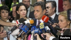 Brazilian Senator Aecio Neves (C) speaks to the media next to Lilian Tintori (R), wife of opposition leader Leopoldo Lopez, Patricia Ceballos (back L), mayor of San Cristobal and wife of jailed former mayor Daniel Ceballos, and opposition leader Maria Corina Machado (2nd L), at the Simon Bolivar airport in Caracas, June 18, 2015.