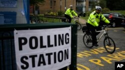 Dua orang polisi (mengendarai sepeda) memeriksa tempat pemungutan suara yang akan digunakan untuk melaksanakan pemilihan umum Inggris, Bermondsey Village Hall di area Jembatan London, London, Kamis, 8 Juni 2017. (AP Photo / Markus Schreiber)
