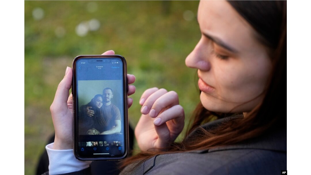 Julija Fedosjuk pokazuje svoju i suprugovu fotografiju tokom intervjua za AP u aprilu 2022. godine.