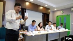 Suon Bunsak, executive secretary of the Cambodian Human Rights Action Committee (CHRAC) holds the pocket version of Cambodia's constitutional law during a press conference on the “stop and consult” campaing about the draft Law on Associations and Nongovernmental Organizations on Monday, May 4, 2015. Representatives of some 270 NGOs and INGOs sat in a panel during the press conference on the contoversial proposed law they say is aimed at restricting their work. (Noeu Vannarin/VOA Khmer)