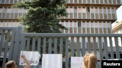 A protester writes "Resignation" on a banner during a demonstration outside Bulgaria's national radio building in Sofia, Bulgaria, Sept. 13, 2019. 