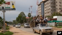 FILE PHOTO - Cambodian passengers sit on top of a pickup truck driven past an unfinished building in Phnom Penh, Cambodia, Monday, Sept. 3, 2007.