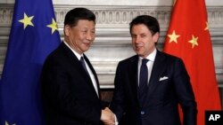 FILE - Chinese President Xi Jinping and then-Italian Prime Minister Giuseppe Conte shake hands after signing a memorandum in support of Beijing's Belt and Road Initiative, in Rome, March 23, 2019. Italy is having second thoughts about renewing the agreement next year.