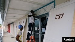Workers install storm shutters before the arrival of Hurricane Dorian in Marsh Harbour, on the Great Abaco Island, Bahamas, Aug. 31, 2019. 