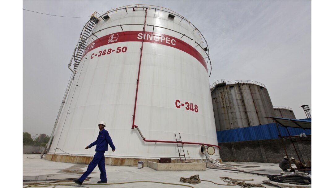 FILE - An employee walks past oil tanks at a Sinopec refinery in Wuhan, Hubei province April 25, 2012.