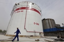 FILE - An employee walks past oil tanks at a Sinopec refinery in Wuhan, Hubei province April 25, 2012.