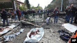 People gather around the entrance of a damaged building after a car bomb blew up at security sites in Damascus, December 23, 2011, in this handout photo released by Syria's national news agency SANA