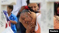 Denise Paba, who lost her 6-year-old niece Veronica Moser, is comforted as she cries at a memorial for victims behind the theatre where a gunman opened fire last Friday on moviegoers in Aurora, Colorado July 22, 2012. 