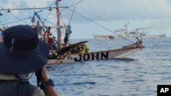 Sebuah kapal Penjaga Pantai China, latar belakang, melewati perahu aktivis dan sukarelawan dari koalisi non-pemerintah bernama Atin Ito di Laut Cina Selatan pada Kamis, 16 Mei 2024. (Foto: via AP)