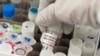 FILE - A researcher lifts a vial with a potential COVID-19 vaccine at Novavax labs in Gaithersburg, Maryland, March 20, 2020, one of the labs developing a vaccine for the coronavirus.