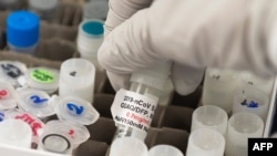 ARCHIVO - Un investigador levanta una ampolla con una posible vacuna contra el COVID-19 en los laboratorios Novavax en Gaithersburg, Maryland, EEUU, el 20 de marzo de 2020, uno de los laboratorios que desarrolla una vacuna contra el coronavirus.