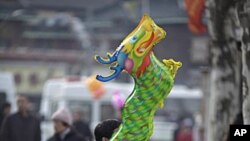 A man holds a dragon balloon outside Longhua Buddhist Temple on the first day of the Chinese Lunar New Year in Shanghai, January 23, 2012.