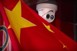A Chinese flag hangs near a Hikvision security camera outside of a shop in Beijing, Oct. 8, 2019.