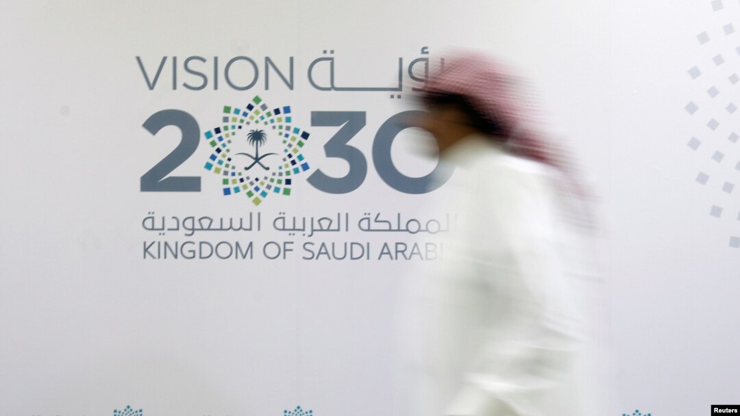 FILE - A man walks past the logo of Vision 2030 after a news conference, in Jeddah, Saudi Arabia, June 7, 2016.