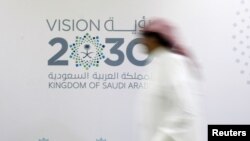 FILE - A man walks past the logo of Vision 2030 after a news conference, in Jeddah, Saudi Arabia, June 7, 2016.