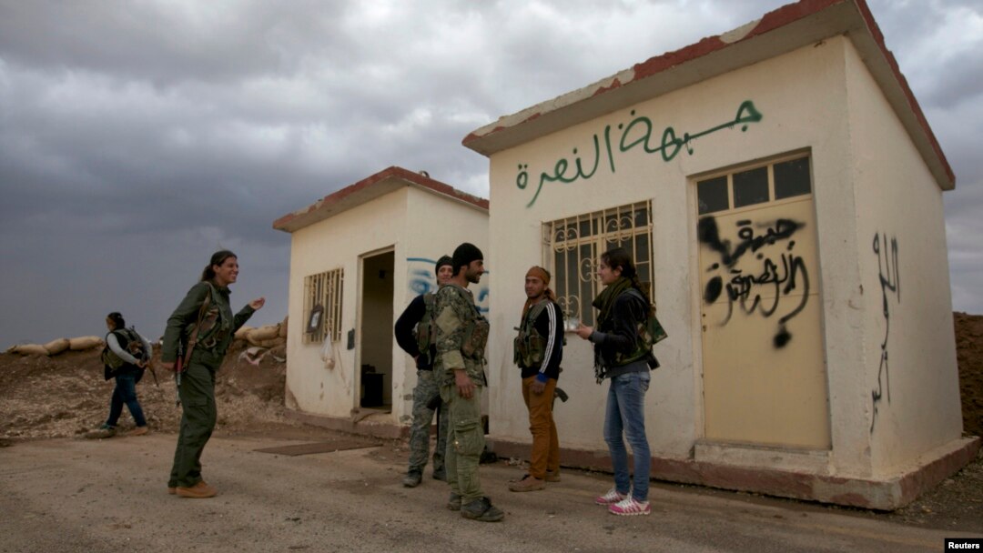 Members of the Kurdish People's Protection Units (YPG) chat together as they stand in front of a base, that used to be for Islamist Syrian rebel group Jabhat al-Nusra, after capturing it from them in Al-Rmelan, Qamshli province, Nov. 11, 2013.