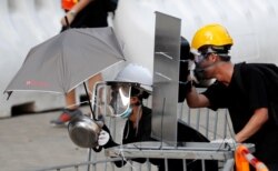 FILE - Protesters use makeshift protective gear to avoid tear gas during the city-wide strike to call for democratic reforms outside Central Government Complex in Hong Kong, Aug. 5, 2019.