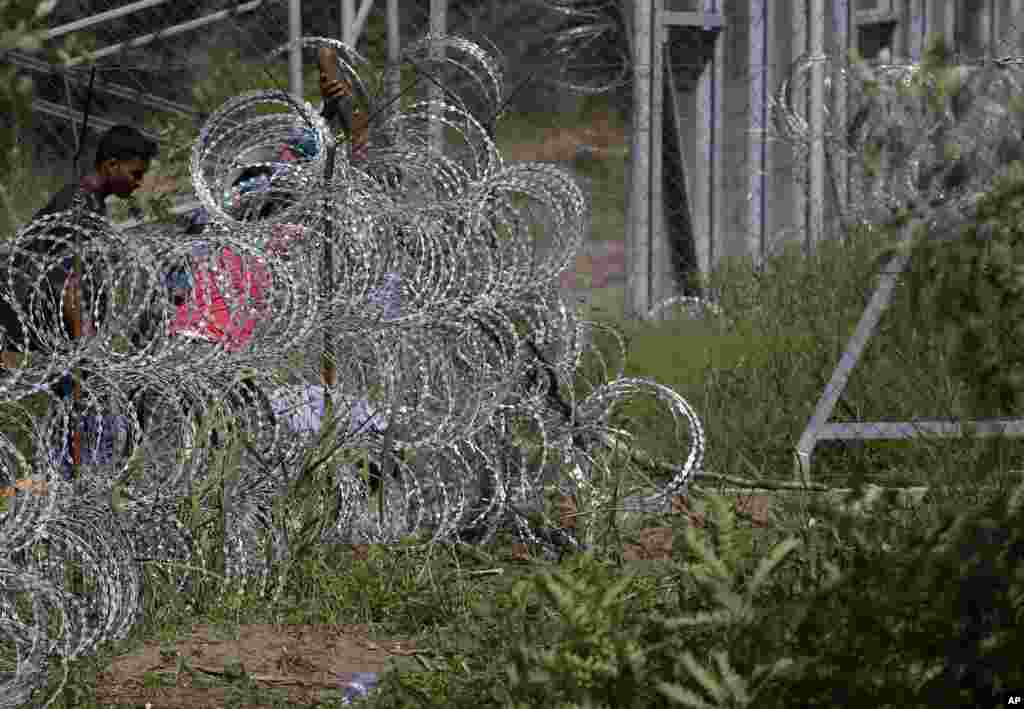 Migrants try to cross under a wire fence on the Serbian border with Hungary, near the village of Hajdukovo, Sept. 7, 2015.