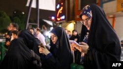 Iranian women check their phones for updates on President Ebrahim Raisi and Foreign Minister Hossein Amir-Abdollahian as people gather to pray for them in Valiasr Square in central Tehran on May 19, 2024.