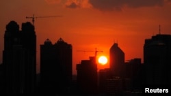 FILE - The sun sets behind buildings under construction in Guangzhou, Guangdong province.