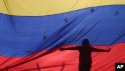 Foto de archivo de las siluetas de manifestantes antigubernamentales a través de una bandera venezolana durante una protesta en Caracas, Venezuela. Julio 10, 2017