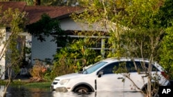 A car sits in high water in front of a home in the aftermath of hurricane Milton, Oct. 10, 2024, in Tampa, Fla. 