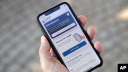 Seseorang memegang smartphone dengan 'Corona Warn-App' (Aplikasi Peringatan Korona) di Berlin, Jerman, Senin, 15 Juni 2020. (AP Photo / Michael Sohn)