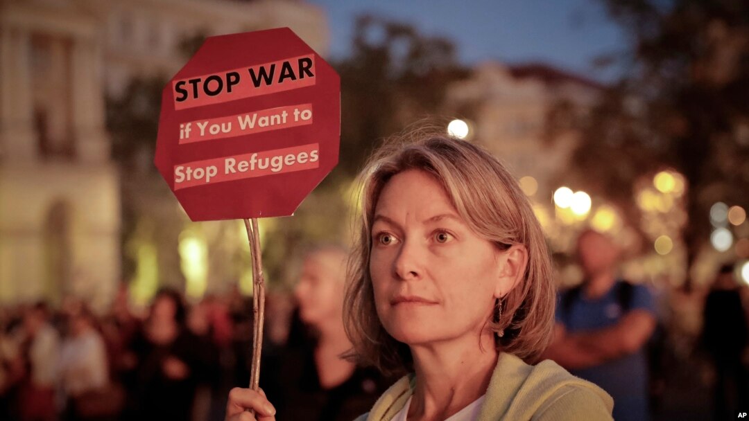 Seorang perempuan di Budapest, Hongaria, memegang papan bertuliskan seruan protes terhadap kebijakan Perdana Menteri Viktor Orban mengenai migran (30/9). (AP/Vadim Ghirda)
