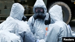 Soldiers wearing protective clothing gather after removing vehicles from a car park in Salisbury, Britain, March 11, 2018. 