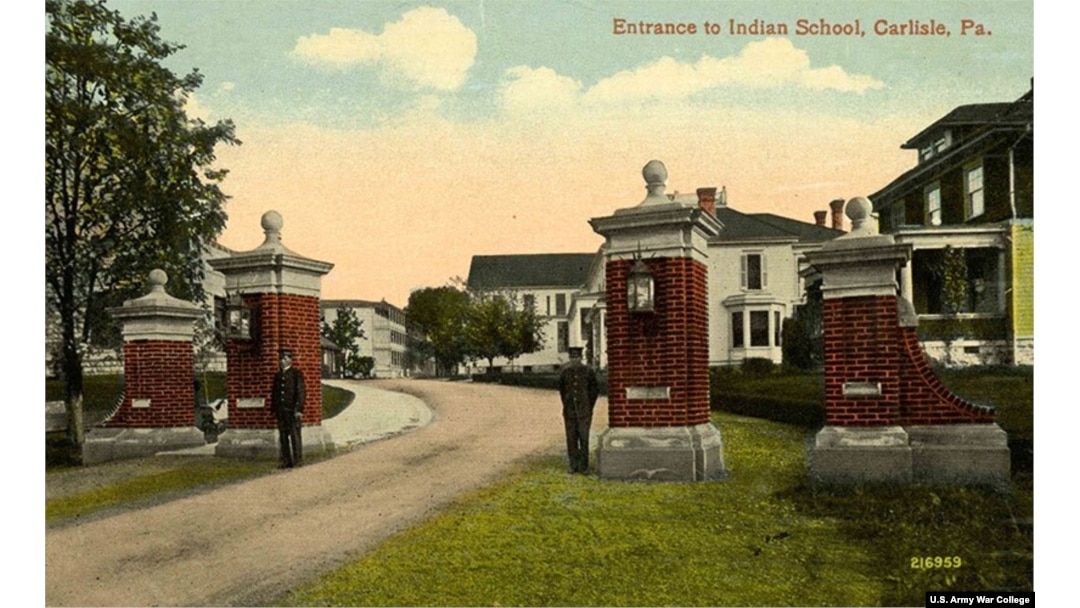 Postcard showing students guarding main entrance, Carlisle Industrial Indian School, Carlisle, Pa. The brick and marble gates were built by Carlisle students in 1910 and still stand today.