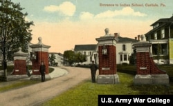 Postcard showing students guarding main entrance, Carlisle Industrial Indian School, Carlisle, Pa. The brick and marble gates were built by Carlisle students in 1910 and still stand today.