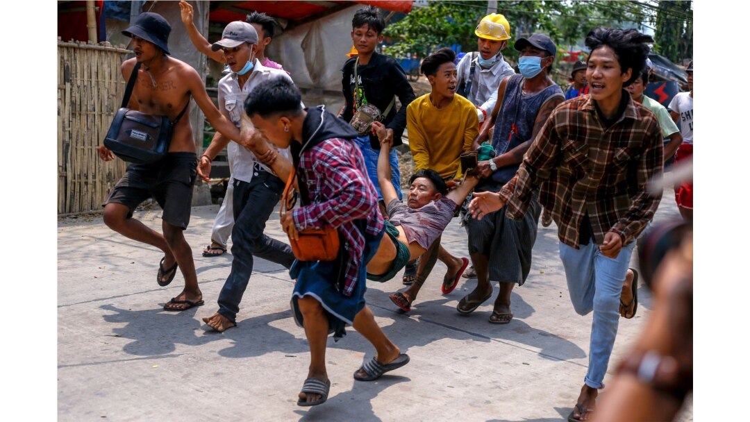 Protesters carry an injured man after riot policemen and soldiers shot rubber bullets during a crackdown on demonstrations in Yangon, Myanmar, March 14, 2021.