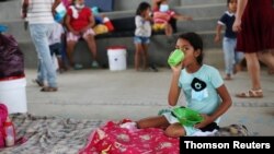 Una niña migrante venezolana lleva su comida al interior de un coliseo donde está instalado un campamento temporal, luego de huir de su país por operaciones militares, según la agencia colombiana de migración, en Arauquita, el 27 de marzo de 2021.